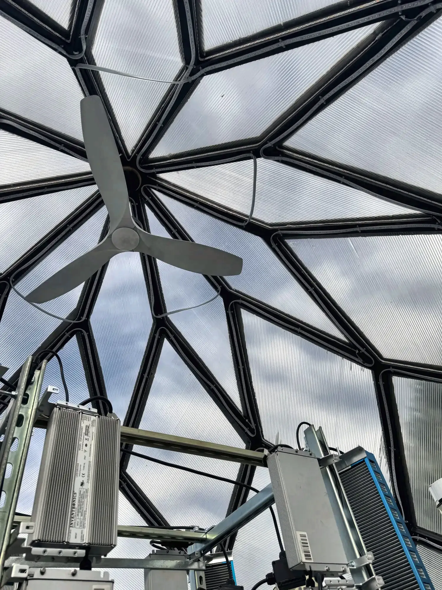 Looking straight up inside the zome: black struts radiate from the apex in a ten-point star, with a ceiling fan below.