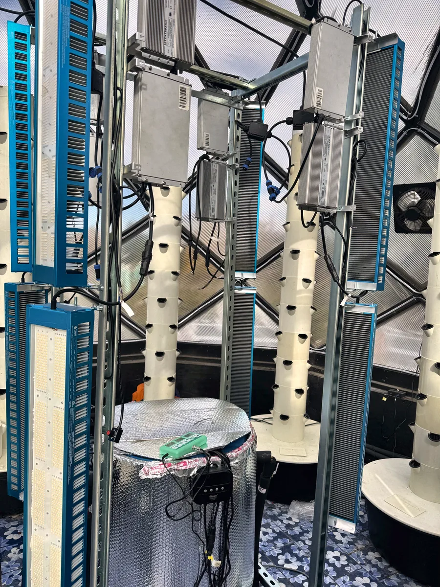 Inside the zome: a foil-wrapped nutrient barrel in the center of a galvanized light rack, with towers and LED bars around it.