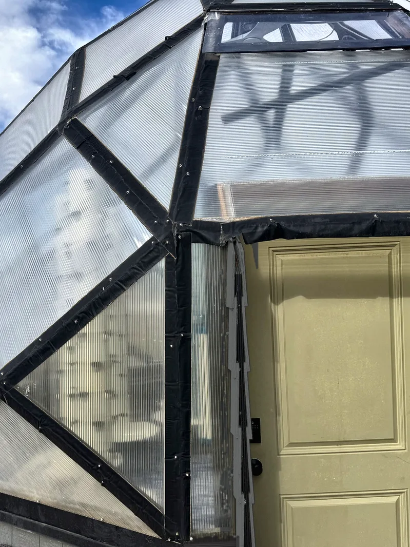 Front of the zome with the sage door set into the pony wall under its overhang.